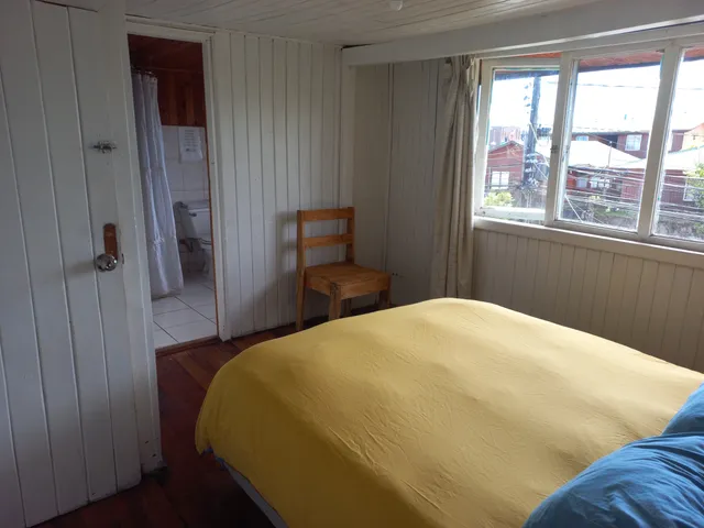 Habitación luminosa con cama matrimonial, piso de madera y baño privado, ideal para quienes buscan comodidad y privacidad — Rapa Nui — Hostal Micelio, Villarrica.